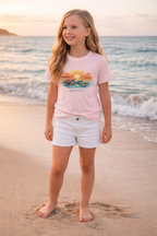 Happy kid wearing ocean themed turtle sunset t-shirt during seaside sunset, summer kids fashion