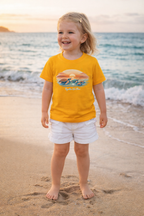 Child modeling colorful sea turtle beach t-shirt with “Together We Flow” slogan near ocean waves