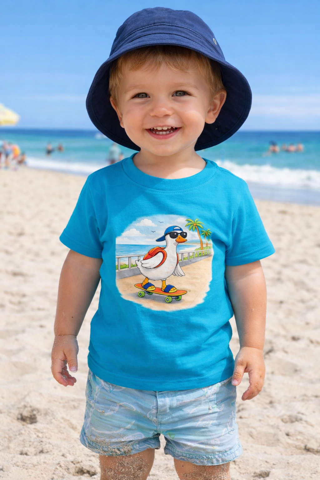 Toddler boy wearing blue duck skateboard t-shirt on beach, kids summer holiday outfit, family matching vacation shirt