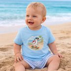 12 month old baby boy wearing blue duck skateboard graphic t-shirt on beach, fun summer kids outfit matching family tee