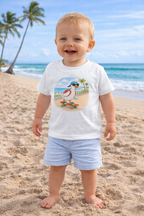 18 month old toddler boy wearing white duck skateboard t-shirt standing on beach, cute summer outfit matching family shirts